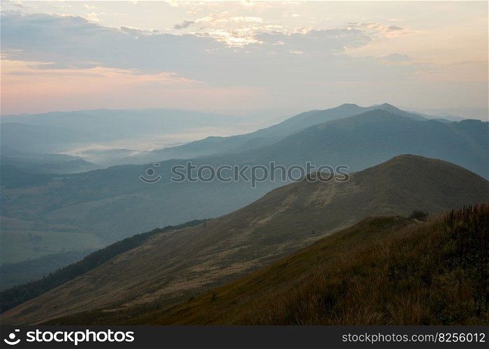 Mountain landscape. Scenic view of mountain peaks, slopes, hills and valleys covered with foggy slopes and valleys. Panoramic view. Natural scenery. Beautiful background