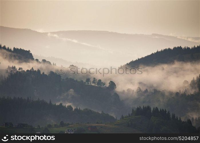 Mountain landscape shortly after rain. Clouds of fog. Misty village on the pass.