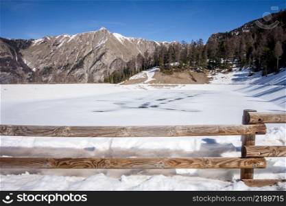 Mountain landscape under snow in winter and frozen lake. Mountain lake landscape in winter