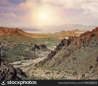 Mountain landscape with a gold mining area in a valley at sunset.