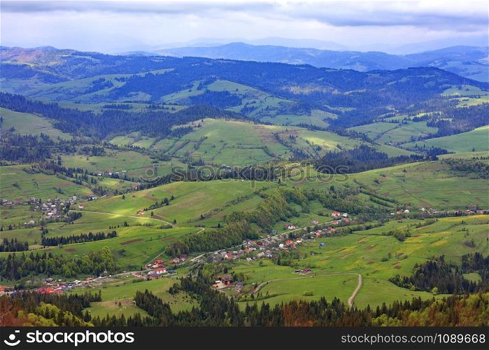 Mountain landscape with a view of the village and ski lift in the spring from a mountain peak, nature in the Carpathian mountains.. Beautiful landscape of the Carpathian mountains, Ukraine. View of the village from the top of the mountain.
