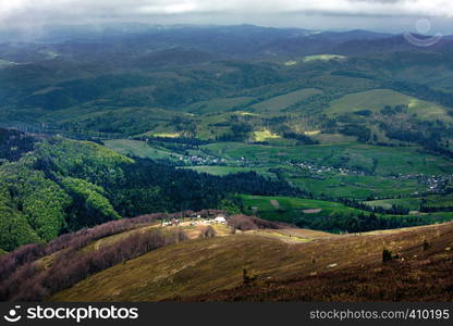 Mountain landscape with a view of the village and ski lift in the spring from a mountain peak, nature in the Carpathian mountains.. Beautiful landscape in Pilipetc mountains, Ukraine. View of the village and ski lift from the mountain top of the Carpathian Mountains.