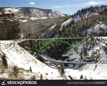 Mountain landscape with bridge crossing over roadway.