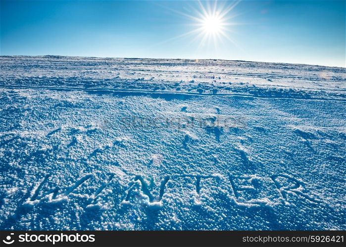 "Mountain landscape with word "winter" on the snow over shining sun on bright blue sky"