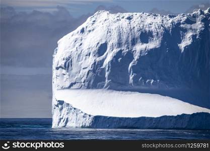Mountain of ice and snow as a tall tower floats in the sea
