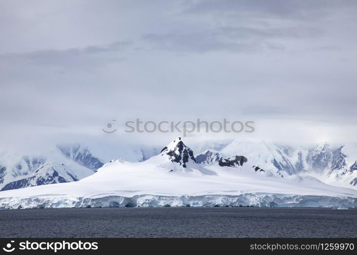 Mountain peaks of mountains covered with ice and snow protrude through cloud cover in Antarctica