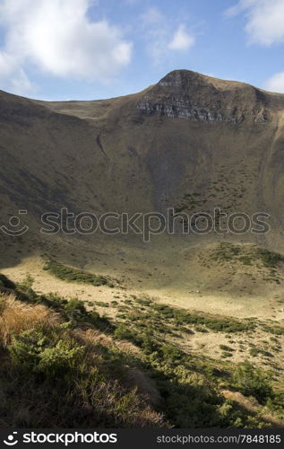 Mountain ravine overgrown with juniper under blue skies