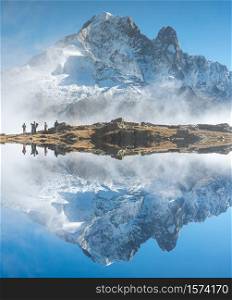 Mountain reflected in the water in the Alps with some people hiking up