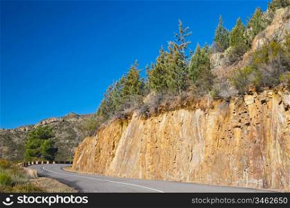 mountain road with sharp curve with blue sky background