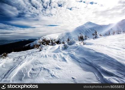 Mountain snow-capped peaks with snow on textured background cloudy sky. Mountain snow-capped peaks with snow on textured