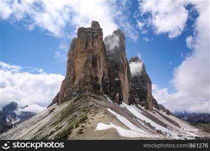 Mountain stock in Dolomites with rock towers as a summit in front of blue sky