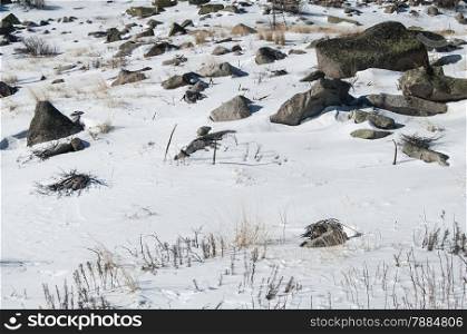 Mountain stones covered with snow in clear winter sunny day as background