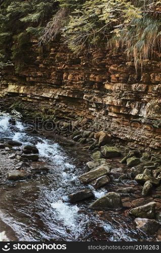 Mountain stream flowing down at rocky wall. Mountain landscape. Natural scene. Beauty in nature