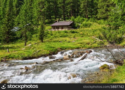 Mountain stream with a small malga in Pejo valley, Trentino, Italy