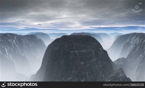 Mountain tops are shrouded in a fog, between them deep abysses. On the sky low dense clouds float. Over the horizon strip of the clear blue sky.