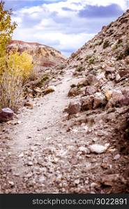Mountain trail in the rocks. Mountain road with stones. Autumn weather under the cloudy sky.