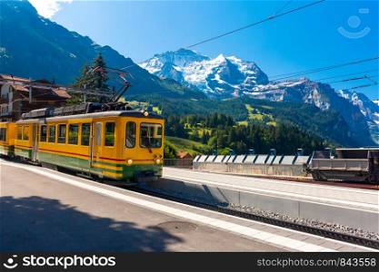 Mountain train on railway station Wengen with view to the peaks of Jungfrau mountain, Switzerland, Bernese Oberland Switzerland. Mountain village Wengen, Switzerland