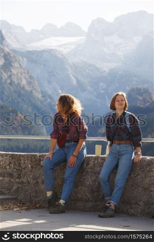 mountain trip. two happy girls on the background of a mountain lake and mountains in the background