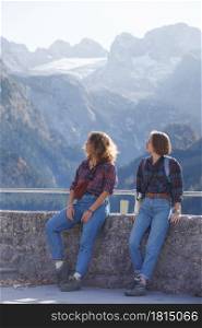 mountain trip. two happy girls on the background of a mountain lake and mountains in the background