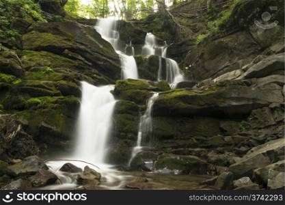 mountain waterfall runs over mossy stones