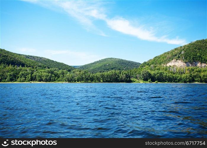 mountain with trees against the blue sky and the river