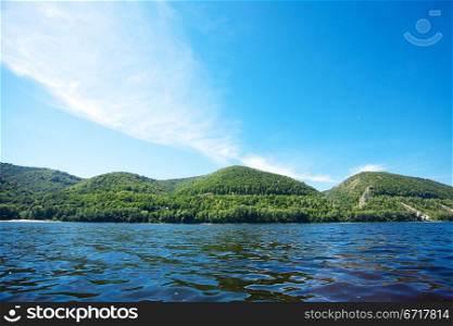 mountain with trees against the blue sky and the river