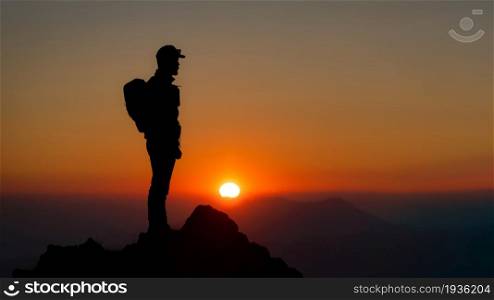 Mountaineer on the top of the mountain watching the fantastic sunset. In silhouettes