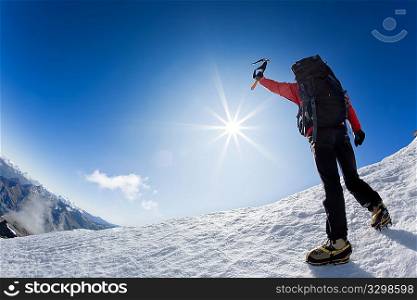 Mountaineer reaching the top of a snowcapped mountain peak, Mt. Grivola, west italian alps, Europe. Horizontal frame.