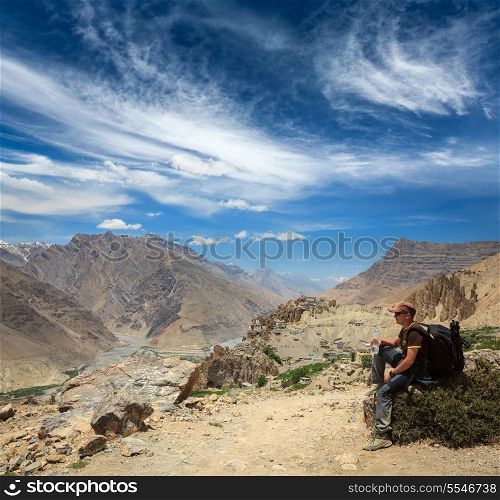 Mountaineer trekker tourist having rest and drinking water in Himalayas mountains - ecotourism concept. Spiti valley. Near Dhankar gompa (monastery), Himachal Pradesh, India