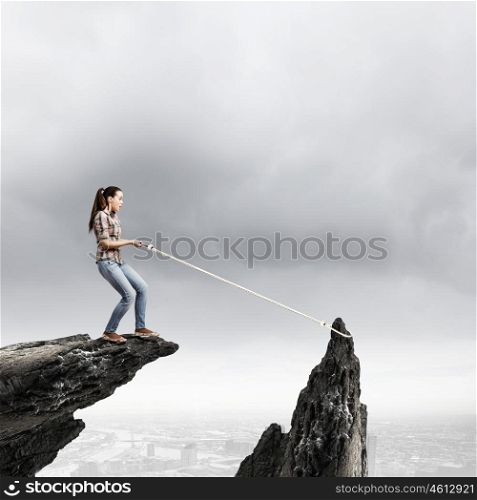 Mountaineering concept. Young woman climbing rock with help of rope