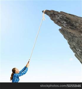Mountaineering concept. Young woman climbing rock with help of rope
