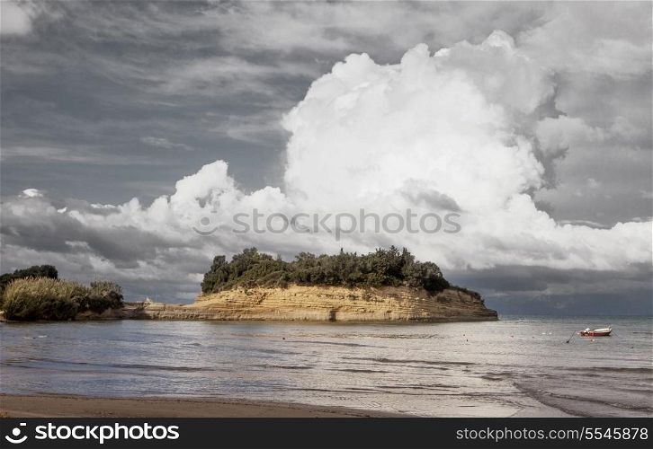 Mountainous clouds rise above a sandstone peninsula at Sidari on the north coast of Corfu, Greece, with a fashionable desaturation applied