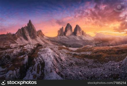 Mountains and beautiful sky with colorful clouds at sunset Autumn landscape with mountains, stones, grass, trails, blue sky with red and orange clouds. High rocks. Tre Cime in Dolomites, Italy. Travel