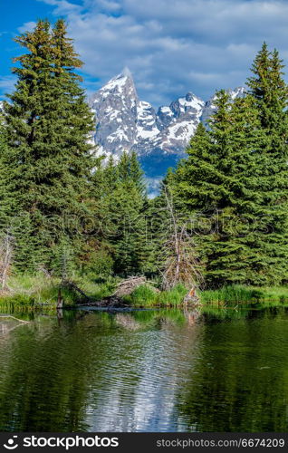 Mountains in Grand Teton National Park with reflection in Snake River. Grand Teton Mountains from Schwabacher&rsquo;s Landing on the Snake River at morning. Grand Teton National Park, Wyoming, USA.