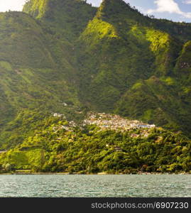 Mountains rise behind lake village of Santa Cruz in Guatemala, Central America