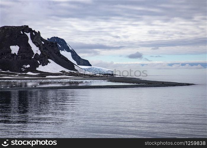 Mountains with white ice glaciers on edge of cold sea in Antarctica