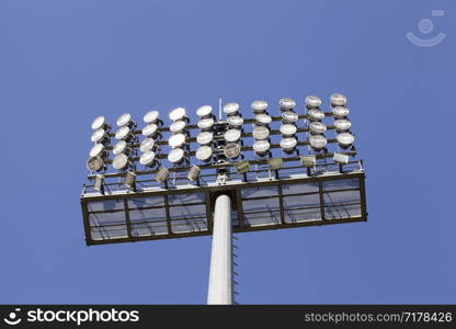 mounted on high concrete pillars huge searchlights on a large football stadium, a day with a blue sky. huge searchlights