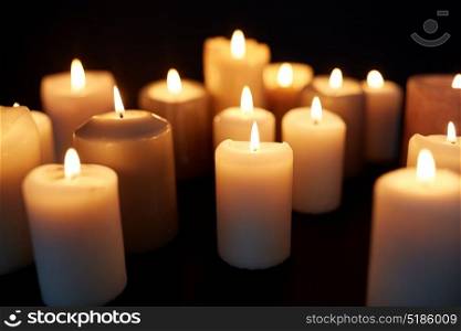 mourning and commemoration concept - candles burning in darkness over black background. candles burning in darkness over black background