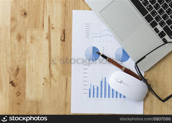 mouse, laptop computer, pen and market analysis business chart document on office desk
