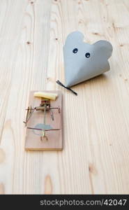 Mouse made of paper and mousetrap with cheese on wood. Good bait catches mice