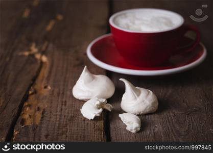 mouth-watering meringue with a cup of coffee on a wooden background