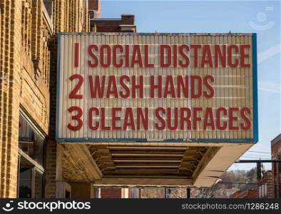 Movie cinema billboard with three basic rules to avoid the coronavirus or Covid-19 epidemic of wash hands, maintain social distance and clean surfaces. Recommendations for avoiding Coronavirus on downtown Main Street cinema