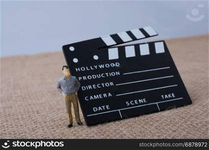 Movie clapper and a man figurine on a canvas