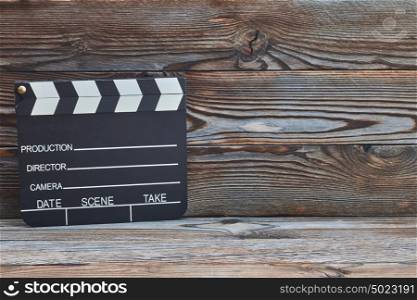 Movie production clapper board over wooden background with copy space