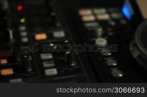Moving closeup pan of DJ decks with mixers and turn tables in a nightclub