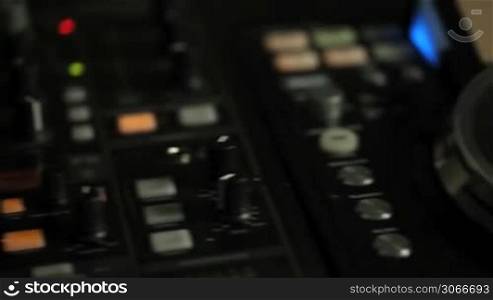 Moving closeup pan of DJ decks with mixers and turn tables in a nightclub