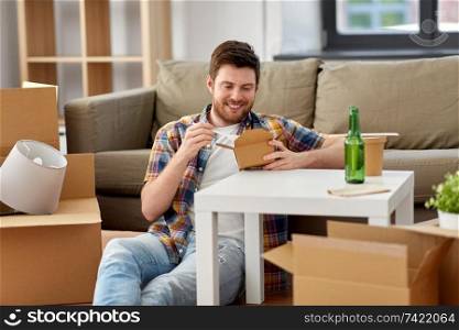 moving, consumption and people concept - smiling man eating takeaway food for lunch at new home. smiling man eating takeaway food at new home