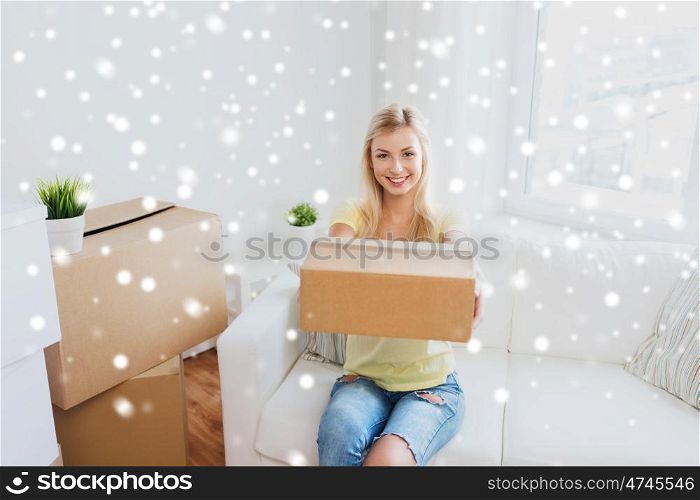 moving, delivery, accommodation and people concept - smiling young woman with cardboard box at home over snow