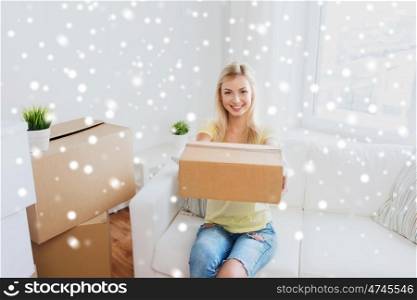 moving, delivery, accommodation and people concept - smiling young woman with cardboard box at home over snow