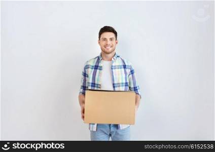 moving, delivery, housing, accommodation and people concept - smiling young man with cardboard box at home